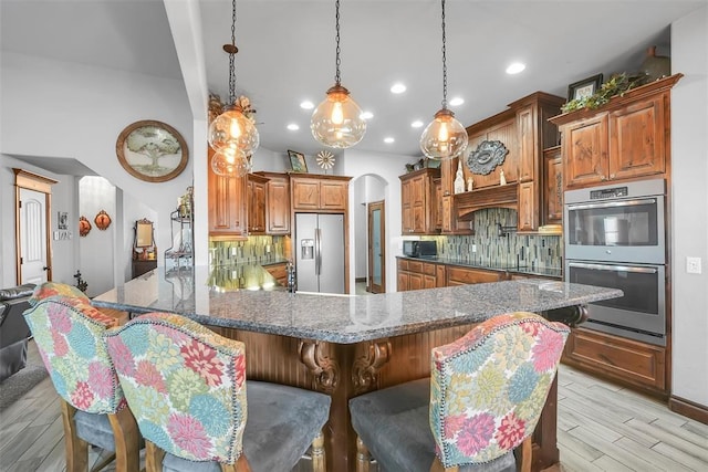 kitchen featuring kitchen peninsula, a kitchen breakfast bar, backsplash, black appliances, and light hardwood / wood-style flooring