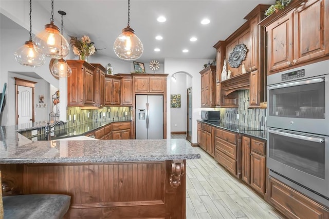 kitchen with kitchen peninsula, decorative backsplash, pendant lighting, and black appliances