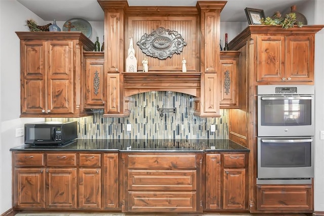 kitchen with dark stone countertops, cooktop, backsplash, and double oven