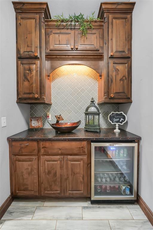 bar with wine cooler, decorative backsplash, and dark stone countertops