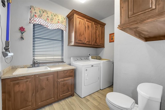 washroom featuring washer and clothes dryer, sink, and light wood-type flooring