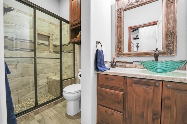 bathroom featuring vanity, toilet, and a shower with door