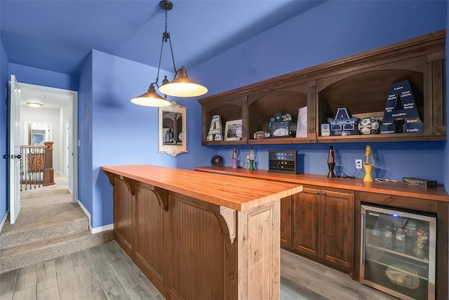 bar with decorative light fixtures, butcher block countertops, light hardwood / wood-style flooring, and beverage cooler