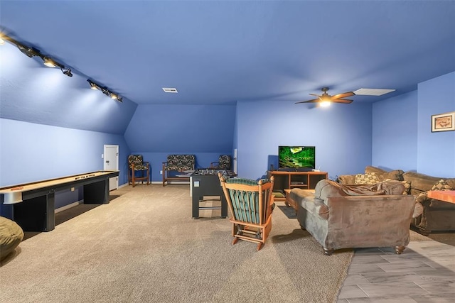 living room featuring ceiling fan, light colored carpet, rail lighting, and vaulted ceiling