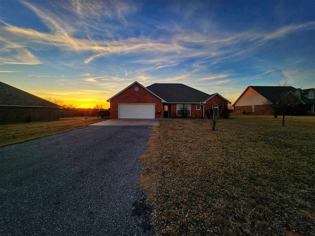 single story home featuring a garage and a yard