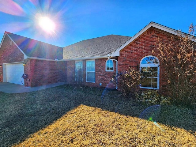 view of front of property featuring an attached garage, brick siding, roof with shingles, and a front yard
