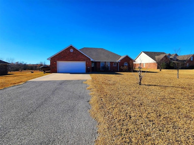 single story home featuring brick siding, an attached garage, gravel driveway, and a front lawn
