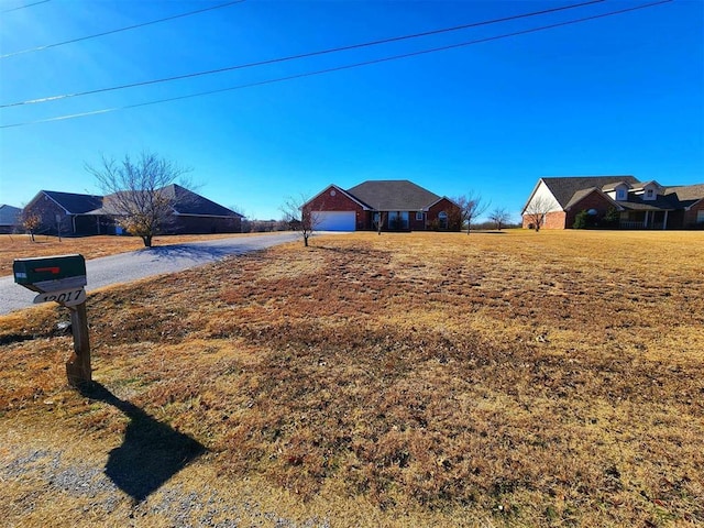 view of yard featuring a garage and aphalt driveway