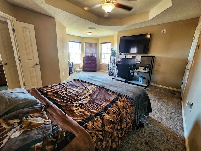 carpeted bedroom with baseboards, a ceiling fan, visible vents, and a raised ceiling