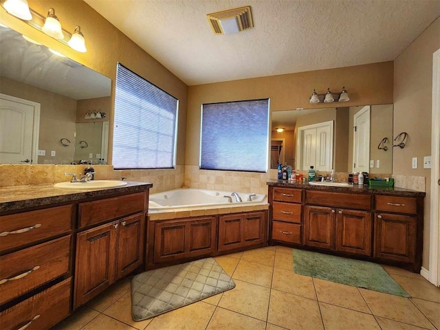 bathroom with a garden tub, tile patterned flooring, a sink, and visible vents