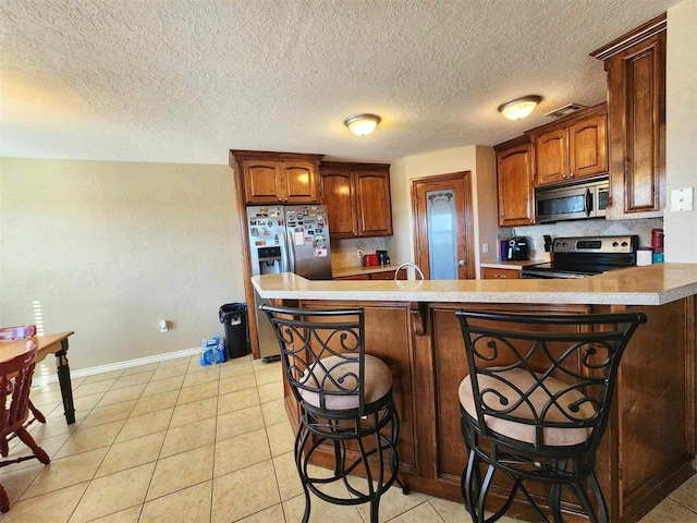 kitchen with light countertops, a kitchen breakfast bar, appliances with stainless steel finishes, and baseboards