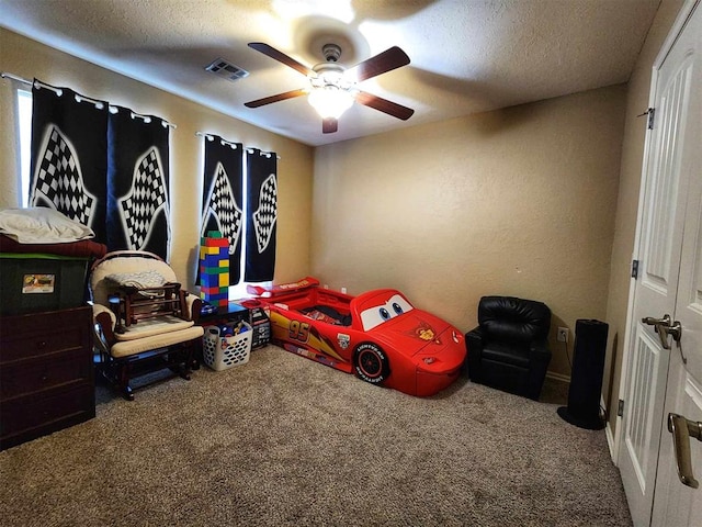 carpeted bedroom with a textured ceiling, visible vents, and a ceiling fan