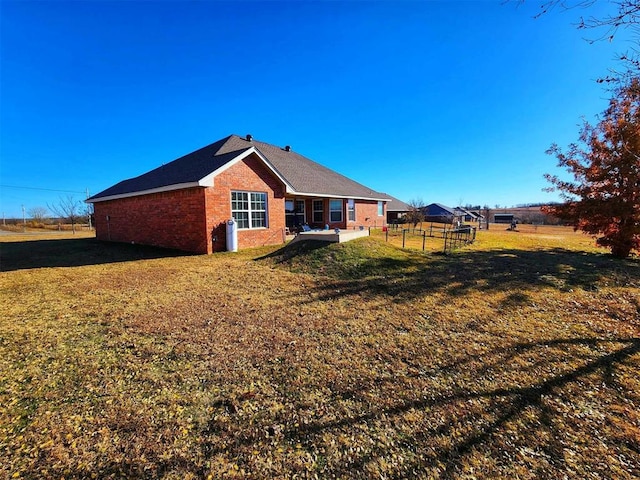 rear view of property with fence, a lawn, brick siding, and a patio