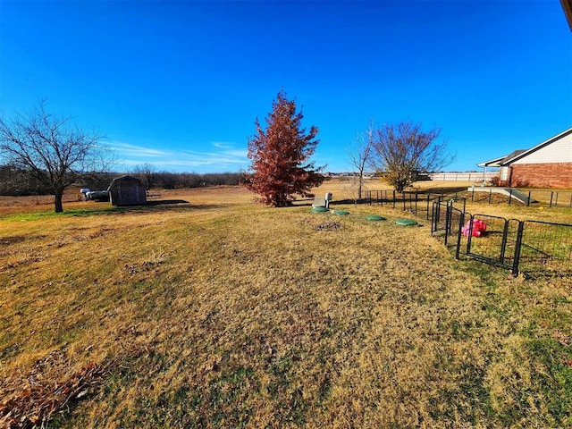 view of yard with fence, an outdoor structure, and a shed