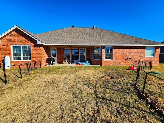 rear view of property featuring brick siding, a yard, a patio area, and a fenced backyard
