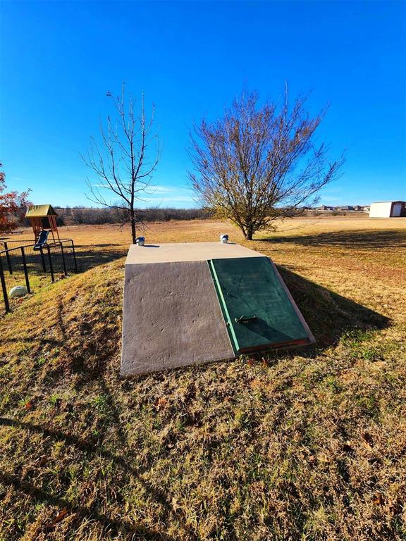 view of storm shelter with a lawn and fence