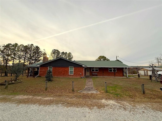 single story home with brick siding, a chimney, and a front yard