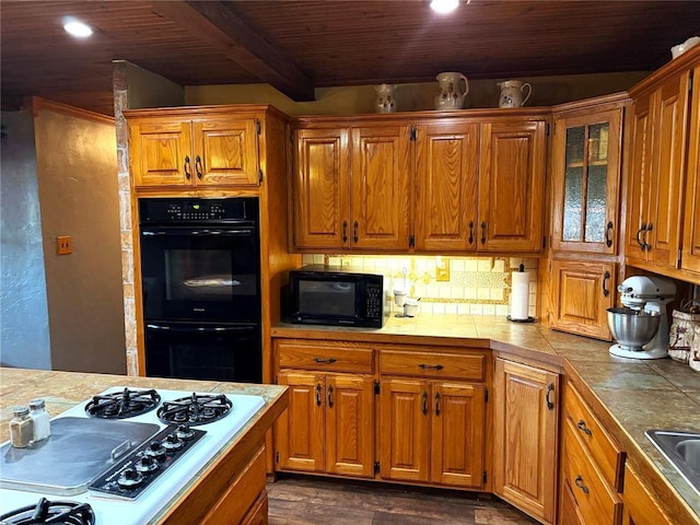 kitchen featuring black appliances, tile counters, and brown cabinets