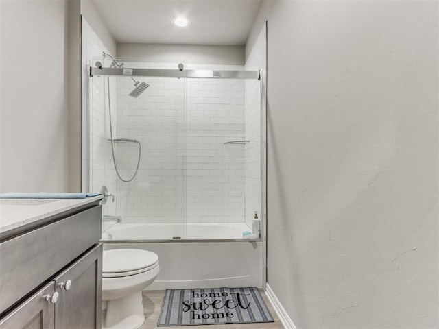 full bathroom with vanity, bath / shower combo with glass door, and toilet