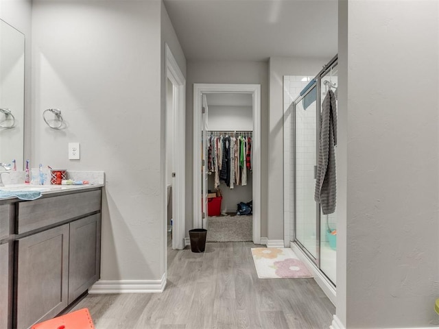 4408 Moonlight Rd, Mustang, OK 73064 - full bathroom featuring wood finished floors, a walk in closet, vanity, and a shower stall
