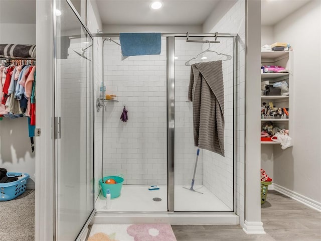 bathroom with a shower with shower door and hardwood / wood-style flooring