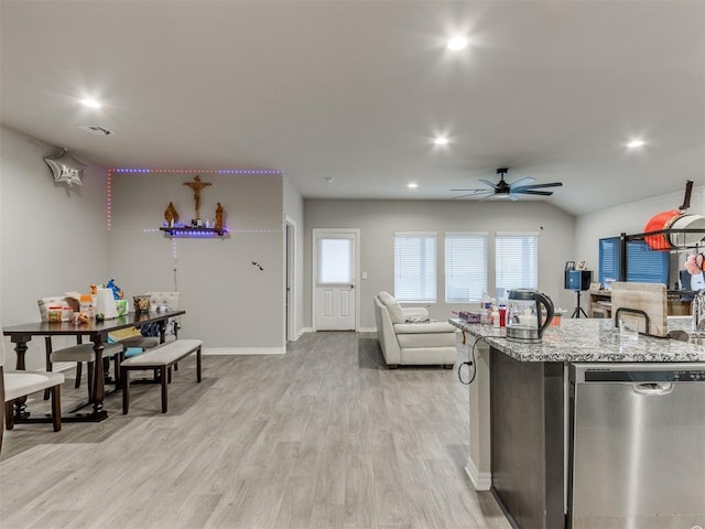 kitchen with ceiling fan, light stone counters, stainless steel dishwasher, lofted ceiling, and light wood-type flooring