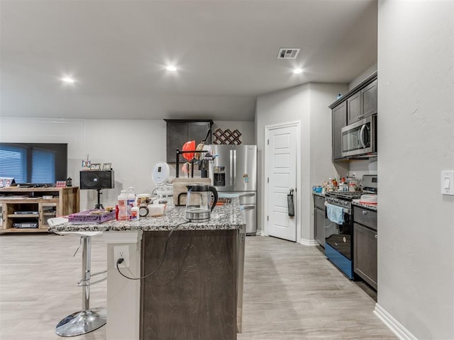 4408 Moonlight Rd, Mustang, OK 73064 - kitchen with stainless steel appliances, light wood-type flooring, light stone counters, a kitchen island, and a kitchen breakfast bar