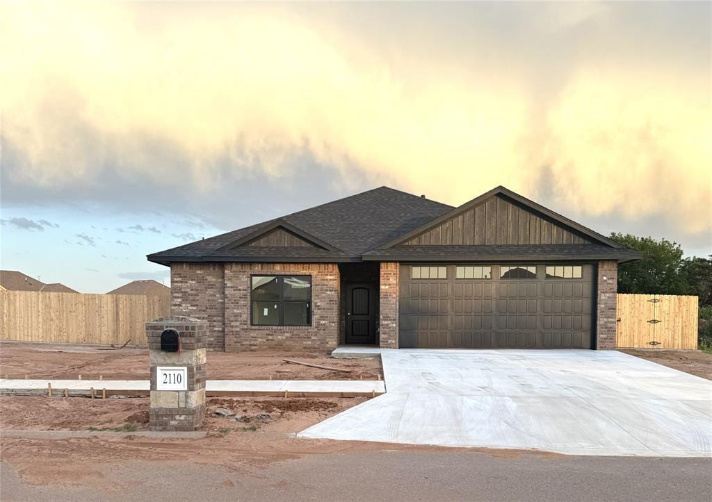 2110 Valley View Rd, Weatherford, OK 73096 - view of front facade with a garage, driveway, brick siding, and roof with shingles