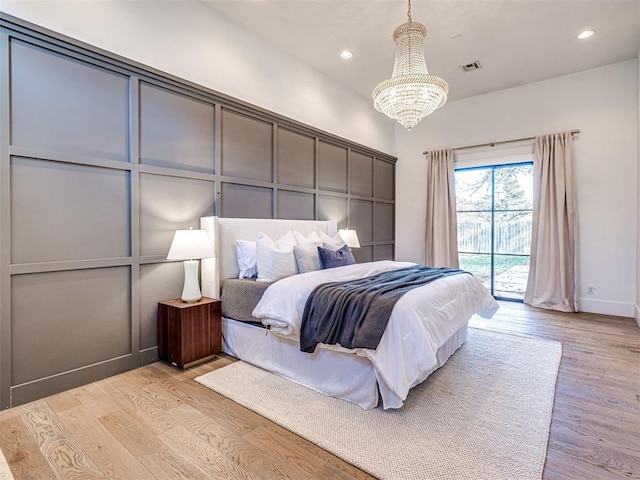 bedroom featuring a notable chandelier, access to outside, and light hardwood / wood-style floors