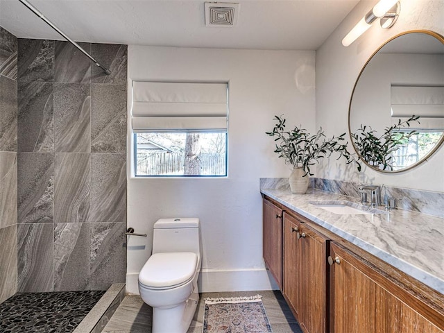 bathroom featuring tiled shower, vanity, and toilet