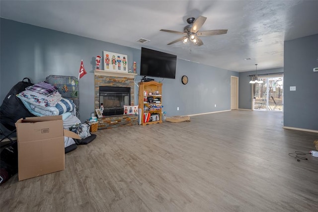 living room with a fireplace, hardwood / wood-style floors, and ceiling fan with notable chandelier