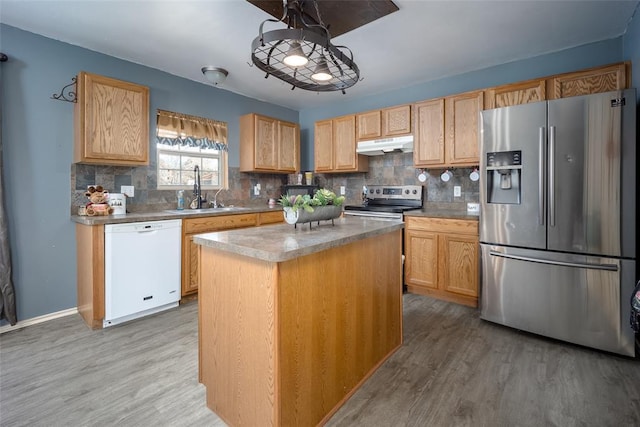 kitchen with hardwood / wood-style floors, a center island, sink, appliances with stainless steel finishes, and tasteful backsplash