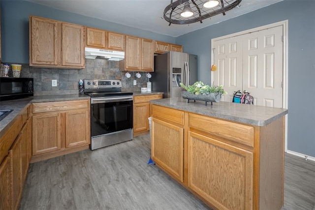 kitchen with decorative backsplash, stainless steel appliances, a kitchen island, and light hardwood / wood-style floors