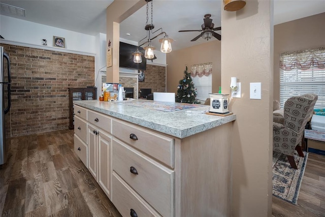 kitchen with ceiling fan, dark wood-type flooring, brick wall, stainless steel fridge, and decorative light fixtures