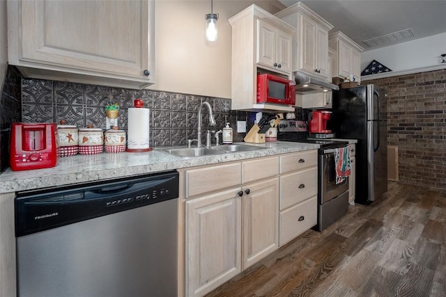 kitchen featuring sink, brick wall, dark hardwood / wood-style floors, decorative light fixtures, and appliances with stainless steel finishes