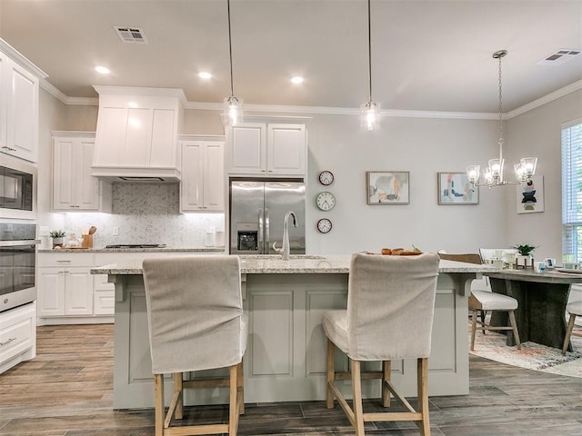 kitchen featuring appliances with stainless steel finishes, a kitchen island with sink, pendant lighting, and a breakfast bar area