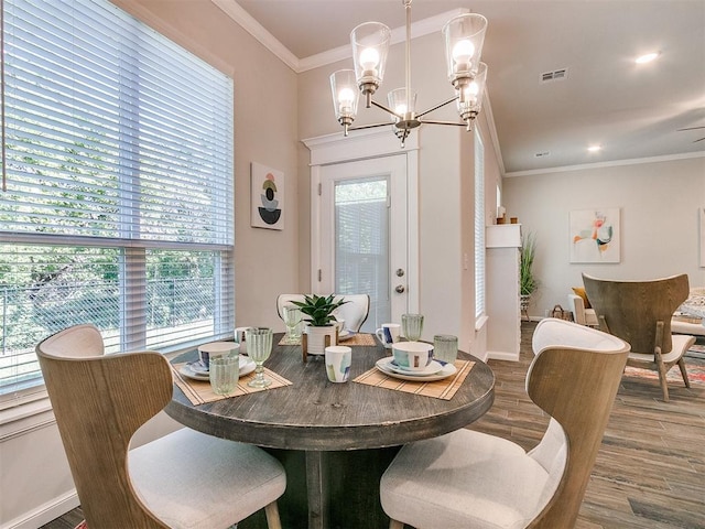 dining room featuring a wealth of natural light, ornamental molding, a notable chandelier, and hardwood / wood-style flooring