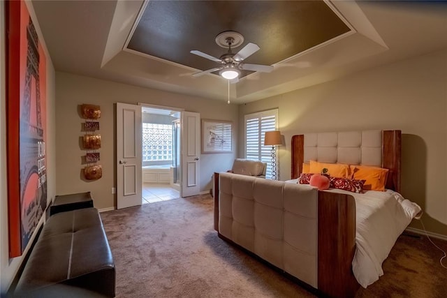 bedroom with a raised ceiling, ceiling fan, and carpet floors