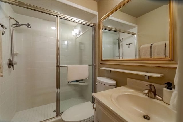 bathroom with a shower with door, vanity, and toilet