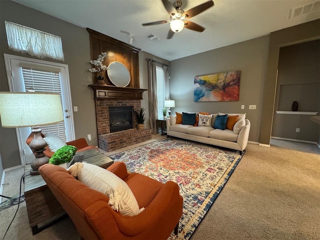 carpeted living room featuring a brick fireplace, plenty of natural light, and ceiling fan