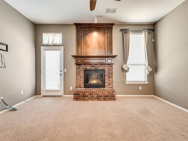 unfurnished living room with a brick fireplace, carpet flooring, and ceiling fan