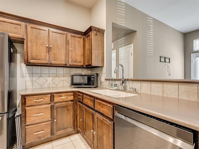 kitchen featuring tasteful backsplash, stainless steel appliances, light tile patterned flooring, and sink