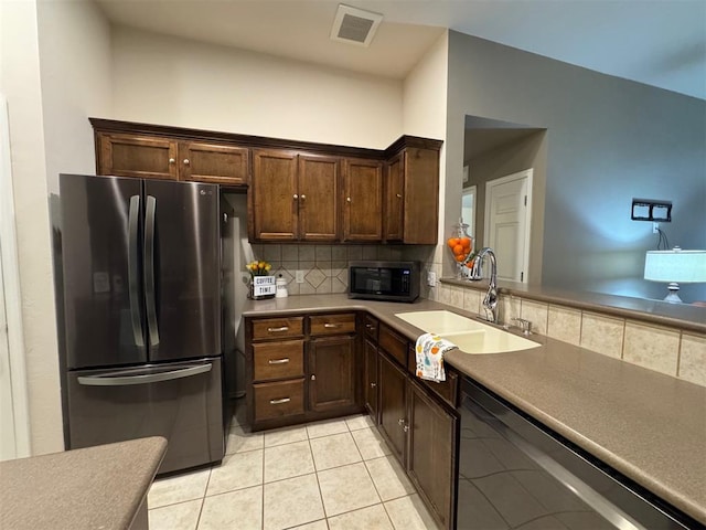 kitchen featuring sink, light tile patterned floors, appliances with stainless steel finishes, dark brown cabinets, and decorative backsplash