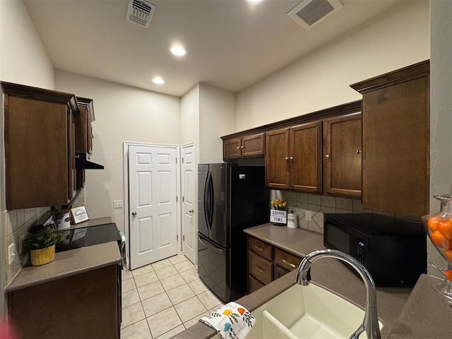 kitchen featuring light tile patterned floors, sink, dark brown cabinets, tasteful backsplash, and black refrigerator with ice dispenser