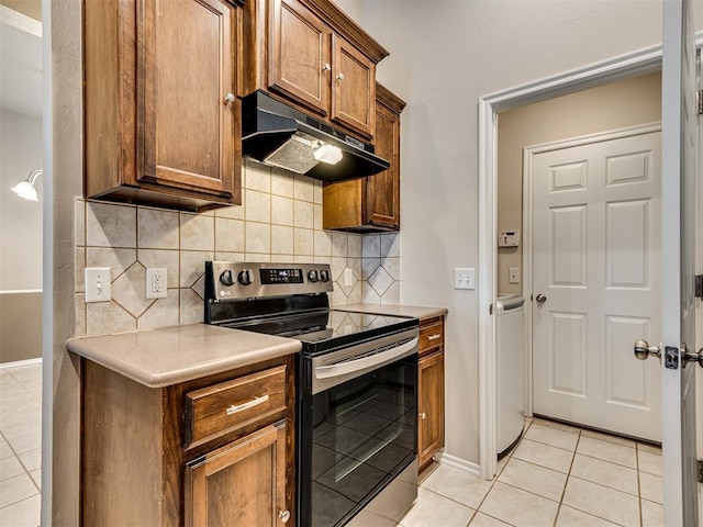 kitchen with electric stove, light tile patterned flooring, and backsplash