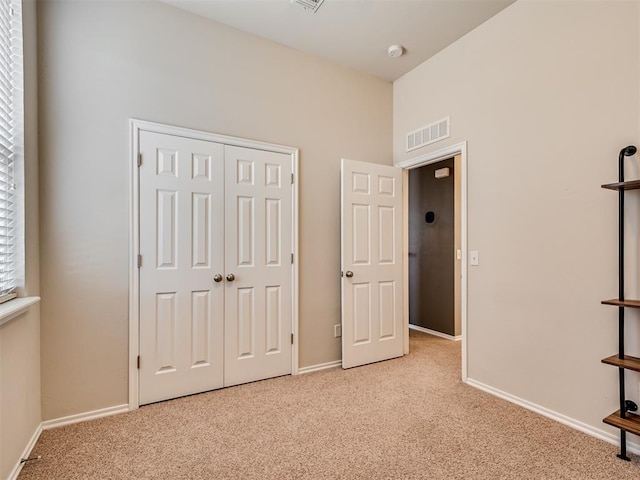 unfurnished bedroom with light carpet and a closet