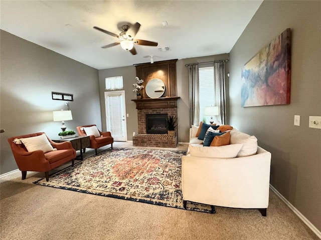 living room featuring a brick fireplace, carpet flooring, and ceiling fan