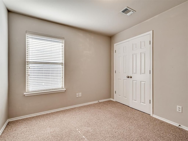 unfurnished bedroom featuring multiple windows, carpet floors, and a closet