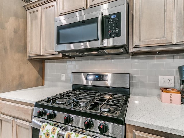 kitchen with light stone countertops, appliances with stainless steel finishes, tasteful backsplash, and light brown cabinetry