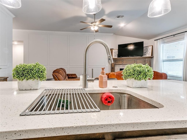 room details featuring light stone counters, crown molding, pendant lighting, and sink